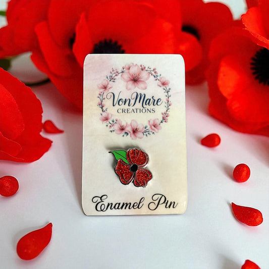 Enamel pin with red flower design on a card labeled 'Von Mare Creations' surrounded by red flowers.