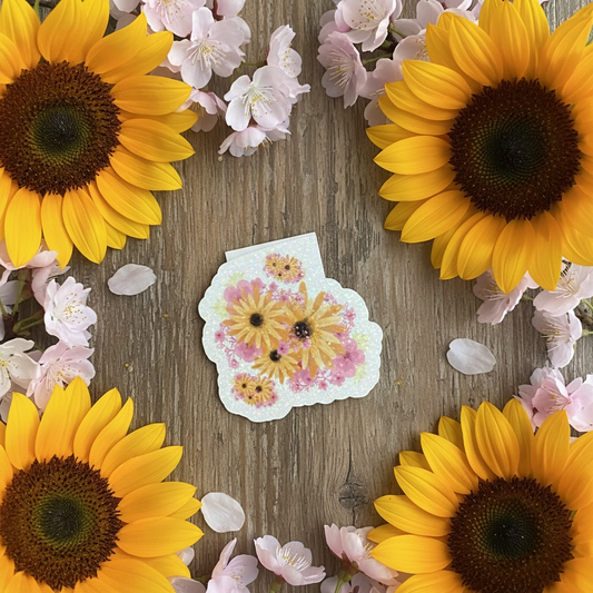 Magnetic bookmark with blossom and sunflower design displayed on a wooden table surrounded by flowers