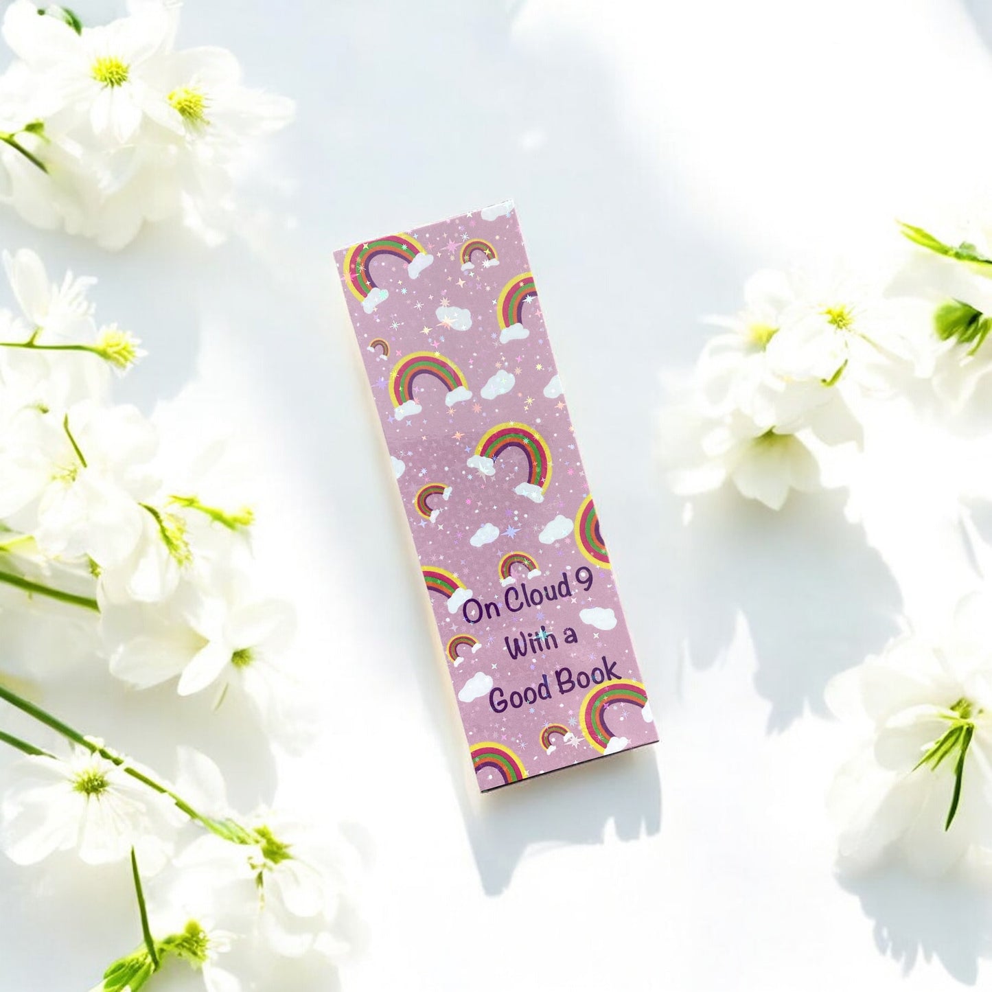 Pink bookmark with rainbow design and text 'On Cloud 9 With a Good Book' on a white floral background
