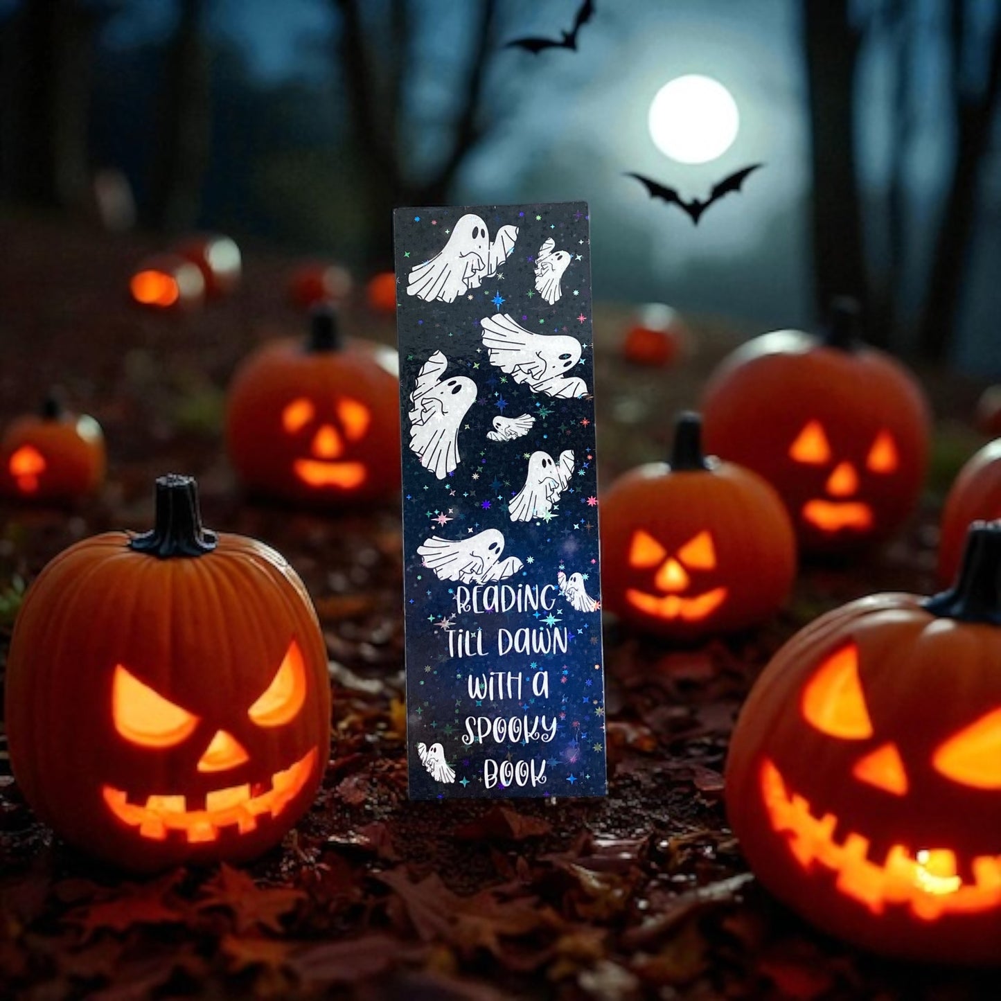 Halloween-themed bookmark with ghosts and text, surrounded by carved pumpkins and bats under a moonlit sky.