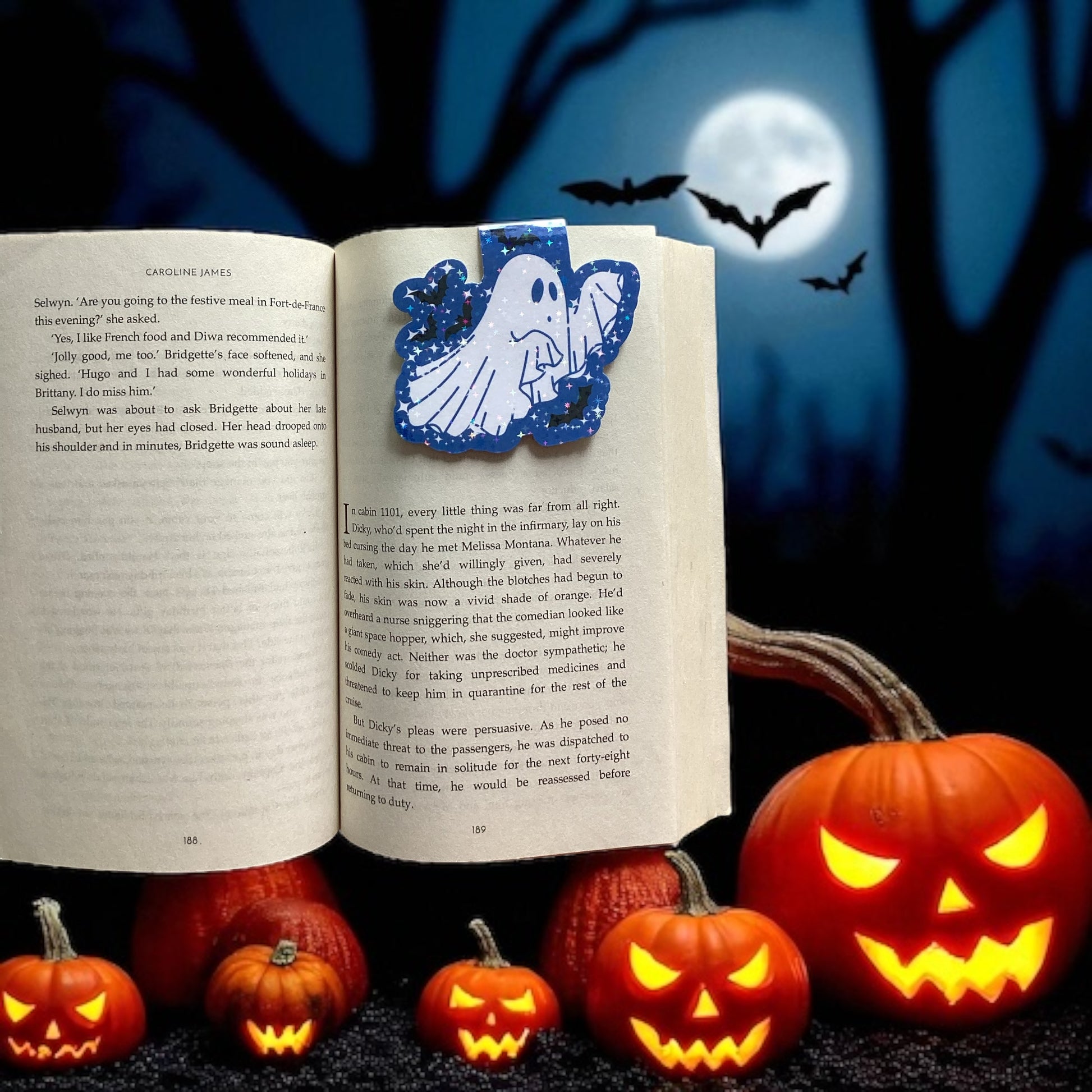 Open book with ghost Magnetic bookmark, surrounded by Halloween pumpkins and bats against a dark background.