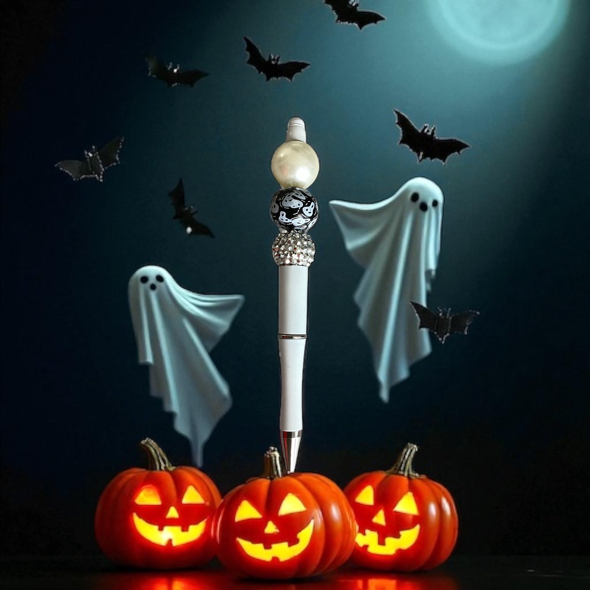 White ghost beaded pen with black ghost-print bead and rhinestone detail, standing upright surrounded by glowing jack-o-lanterns, floating ghosts, and bats against a moonlit Halloween sky"