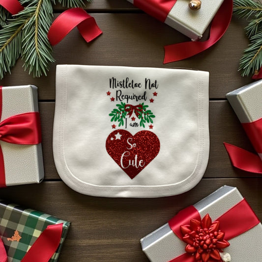 Baby bib with Christmas design on a wooden surface with gift boxes and ribbons